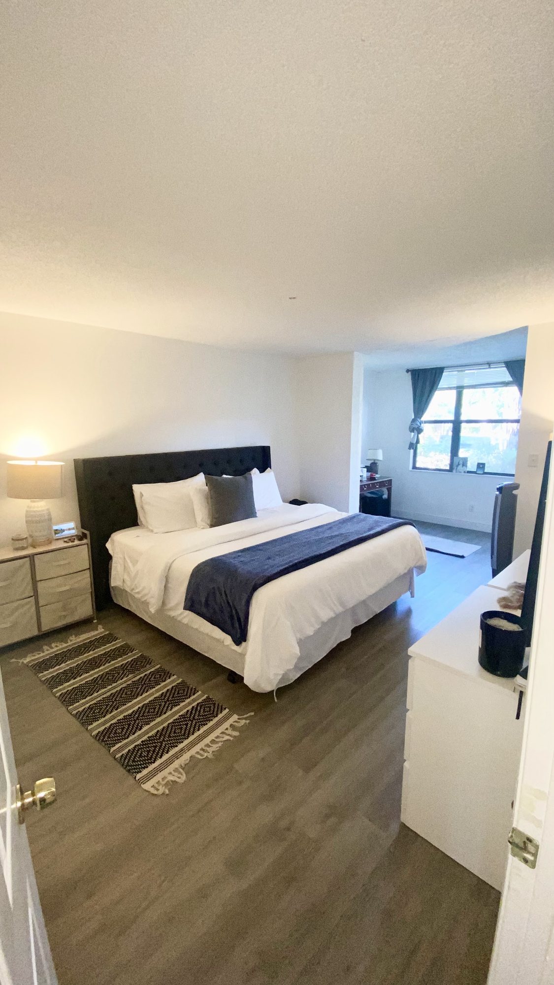 Staged bedroom with made bed, nightstands and natural light