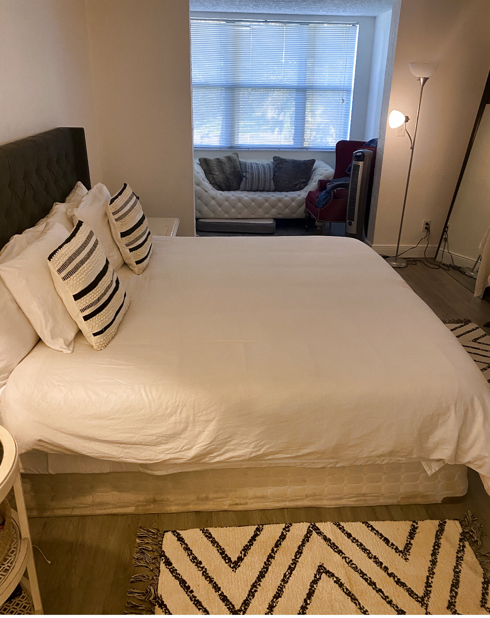 Primary bedroom with a bright window alcove extension furnished as a lounge and reading nook