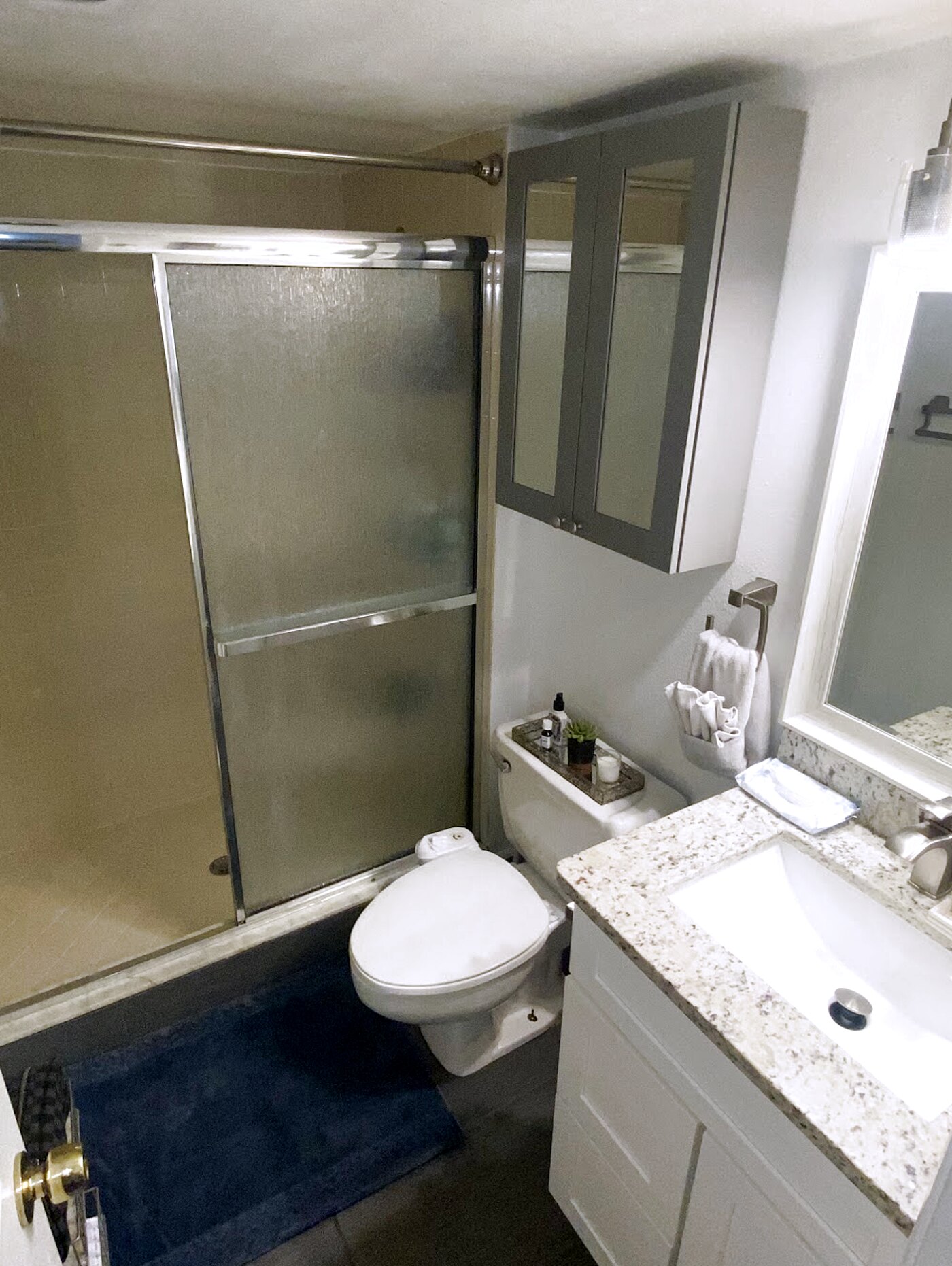 Primary bathroom with granite vanity, framed mirror and glass-door shower